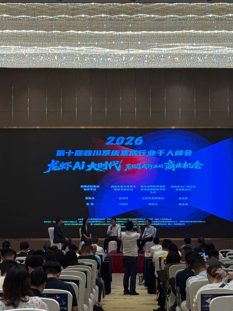 2026 四川系统集成行业千人峰会主席台多人论坛圆桌讨论现场，多位行业嘉宾并排就座、手持话筒交流 AI Agent 趋势，背景为峰会舞台主视觉