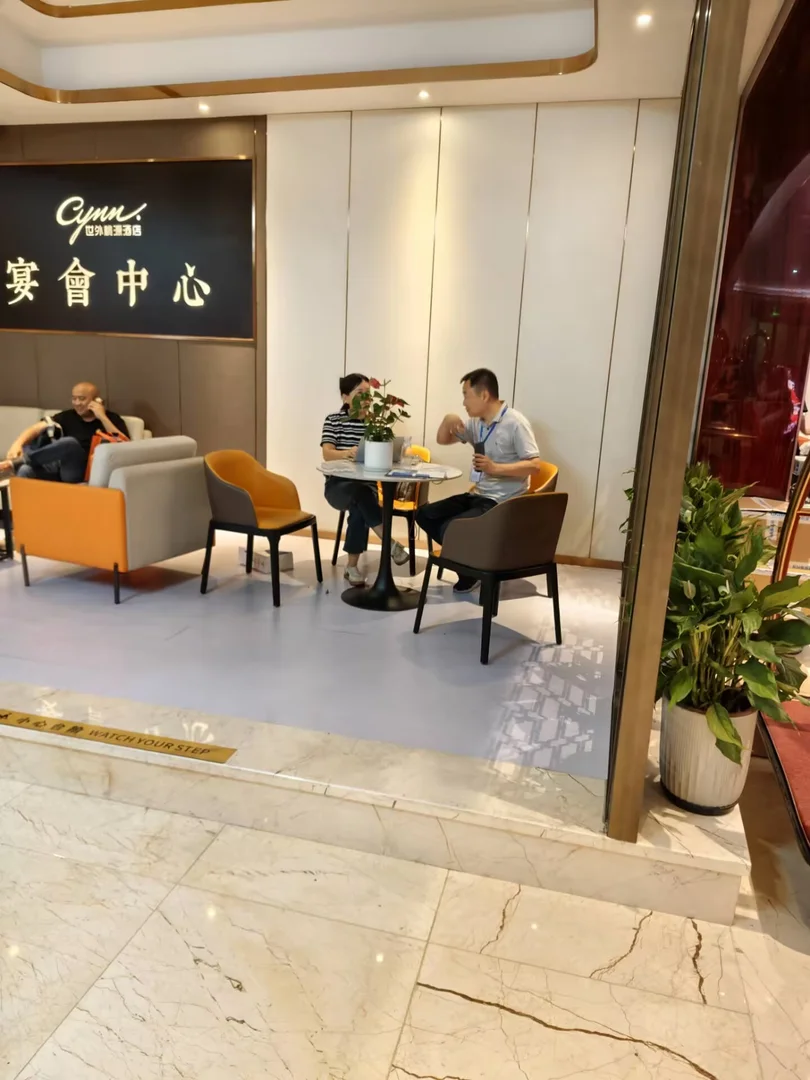 四川网驭数安科技有限公司工程师在 2026 四川系统集成行业千人峰会会场圆桌与潜在客户深度交流，桌面有笔记本电脑、威联通 QNAP 产品资料和茶水，体现非展位深度技术沟通场景